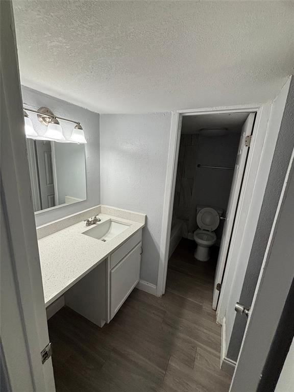 301 Rolston Road, Unit 315101 Irving, TX 75060 - Photo 6 of 12 Vanity area featuring wood-finish flooring, a white vanity cabinet, a light-toned countertop with an integrated sink, a brushed nickel faucet, and a modern light fixture above a mirror