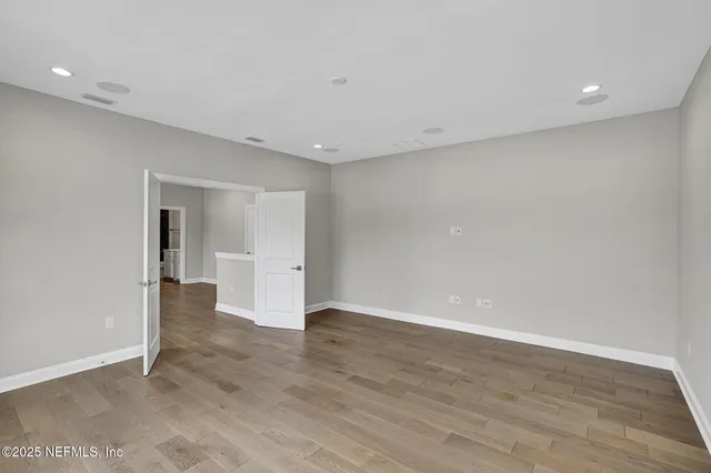 a view of an empty room with wooden floor and closet