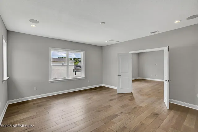 an empty room with wooden floor and windows