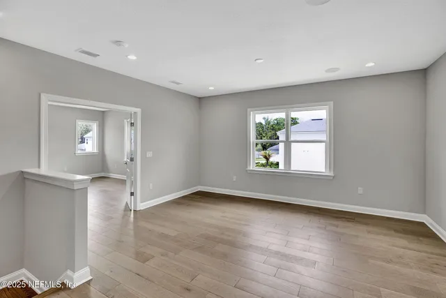 an empty room with wooden floor and windows