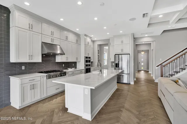 a large white kitchen with stainless steel appliances granite countertop lots of white cabinets a stove and a refrigerator