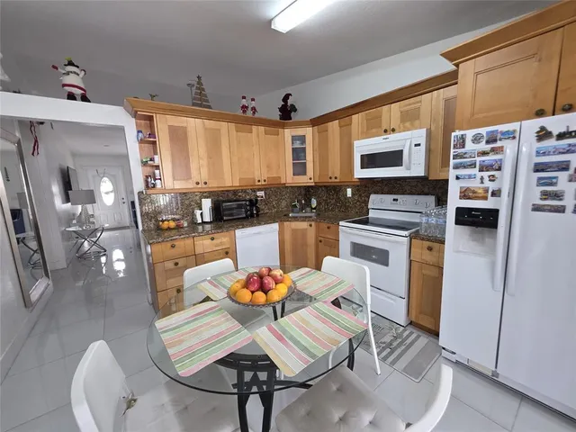 a kitchen with stainless steel appliances kitchen island granite countertop a refrigerator a stove a sink dishwasher with a dining table and chairs with wooden floor