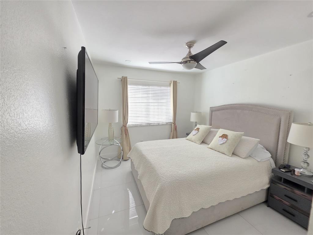 7635 Northwest 181st Street Hialeah, FL 33015 - Photo 9 of 12 a bedroom with a bed and a flat tv screen on the dresser