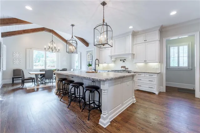 a kitchen with stainless steel appliances granite countertop a stove a sink dishwasher and a dining table with wooden floor