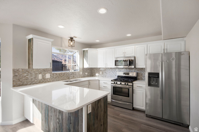 1440 West 100 South Virgin, UT 84779 - Photo 12 of 45 Modern kitchen featuring white cabinetry, light-toned countertops, a mosaic tile backsplash, stainless steel appliances, and wood-finish flooring