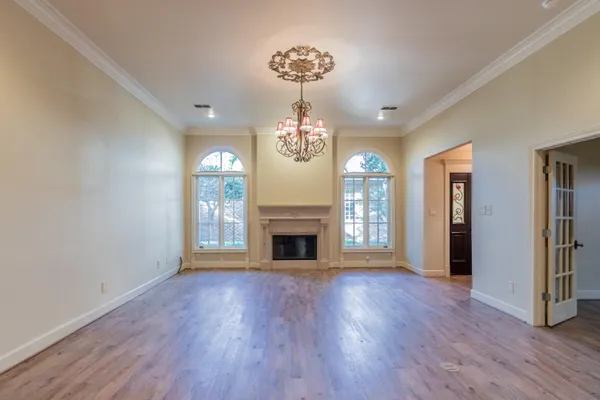 a view of a room with wooden floor fireplace and windows