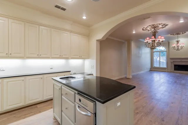 a kitchen that has a sink stainless steel appliances granite countertop a stove and a wooden floors