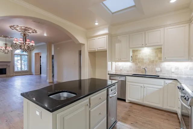 a kitchen with granite countertop a sink stove and cabinets
