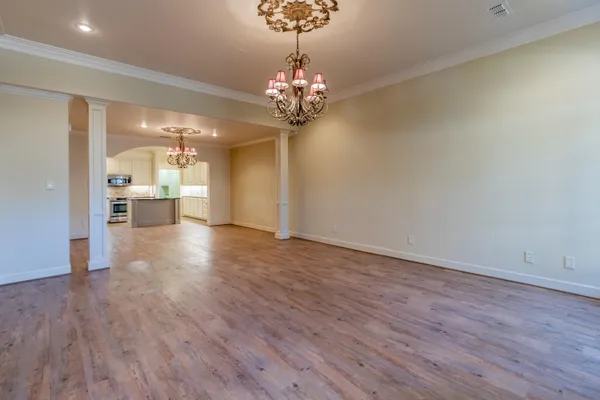 a view of a big room with wooden floor chandelier and windows