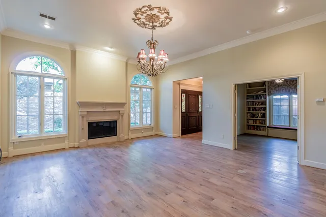 a view of an empty room with wooden floor fireplace and a window