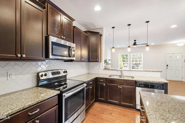 a kitchen with stainless steel appliances granite countertop a sink stove and microwave