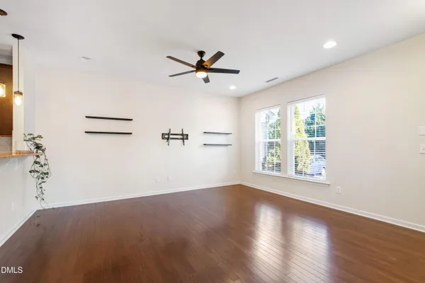 an empty room with wooden floor ceiling fan and windows