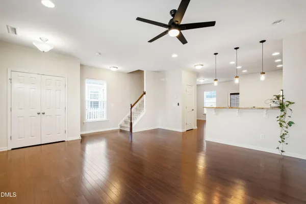 a view of an empty room with wooden floor and a ceiling fan