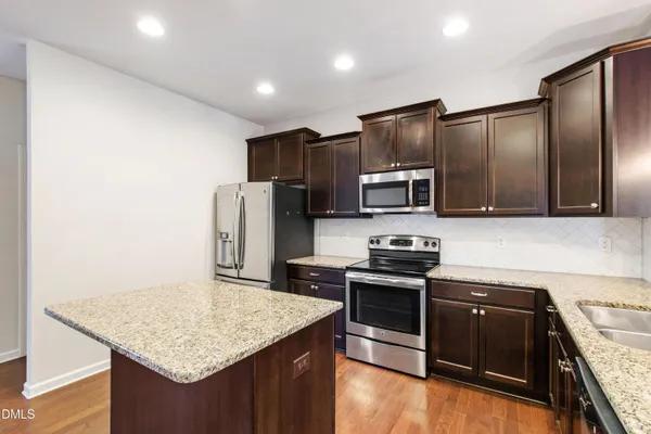 a kitchen with stainless steel appliances granite countertop a stove refrigerator and microwave