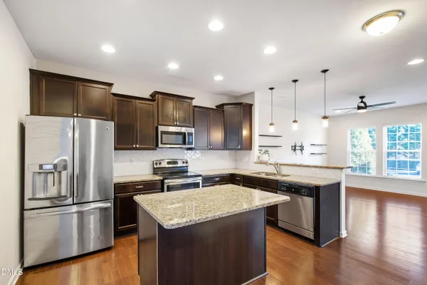 a kitchen with kitchen island a sink stainless steel appliances and refrigerator