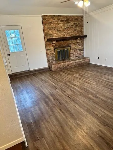 a view of an empty room with wooden floor and a fireplace