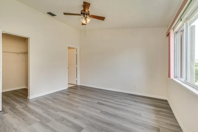 a view of empty room with wooden floor and fan
