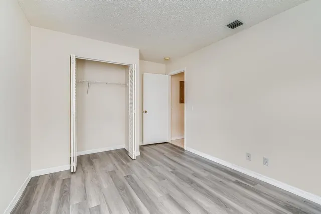 a view of an empty room with wooden floor and closet
