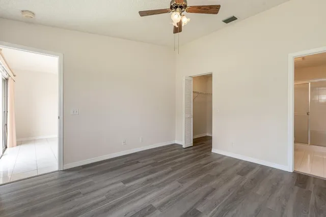 an empty room with wooden floor fan and windows