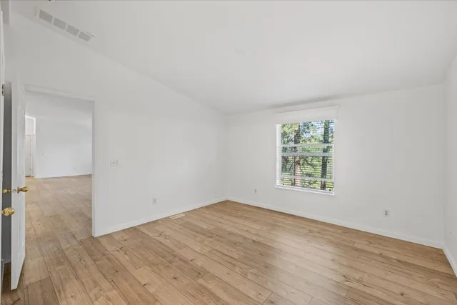 an empty room with wooden floor and window