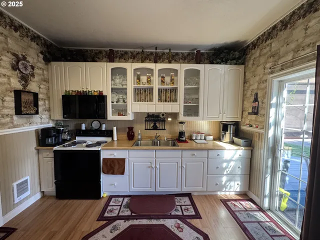 a kitchen with stainless steel appliances a stove a sink dishwasher a microwave oven and a refrigerator with wooden floor