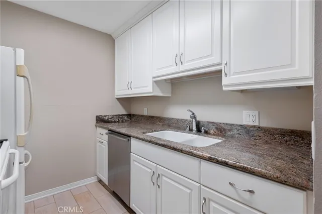 a kitchen with granite countertop white cabinets and a sink
