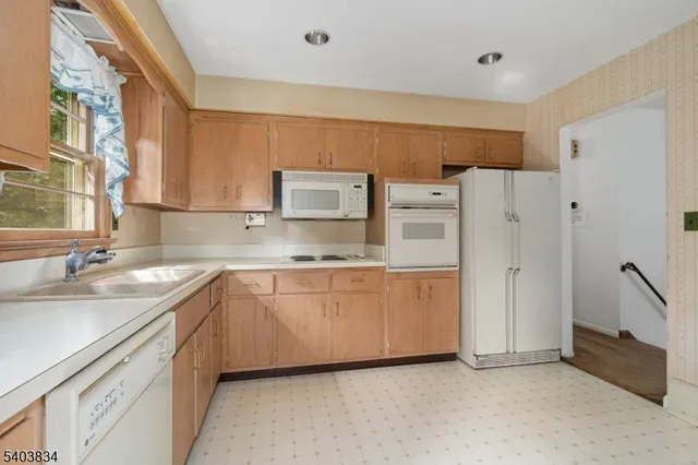 a kitchen with stainless steel appliances granite countertop a refrigerator sink and white cabinets