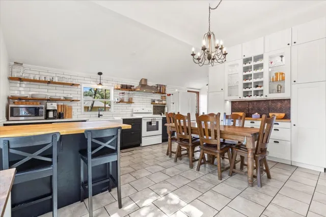 a dining hall with stainless steel appliances a table chairs and a chandelier
