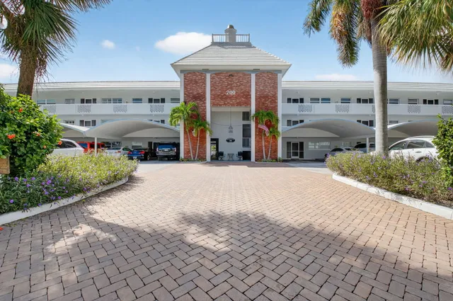 a front view of a building with palm trees