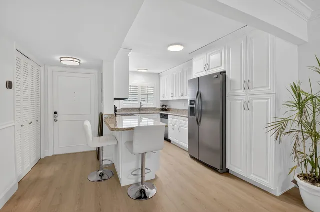 a kitchen with a refrigerator and white table chairs