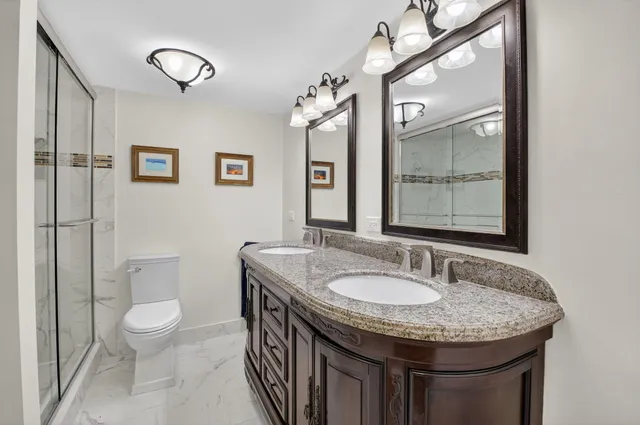 a bathroom with a granite countertop sink a toilet a mirror and shower