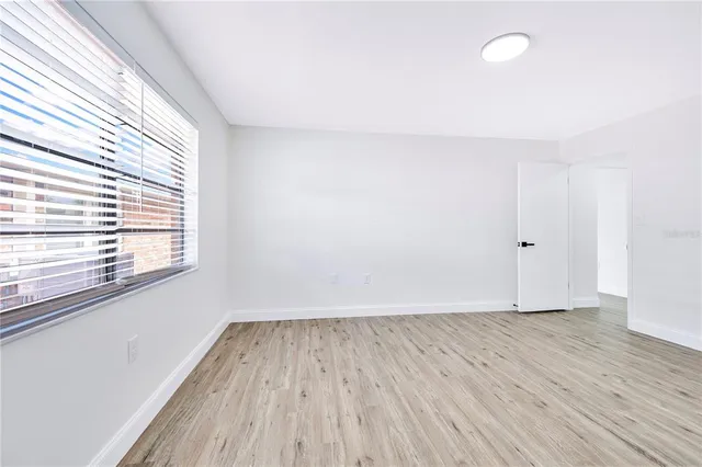 a view of an empty room with wooden floor and a window