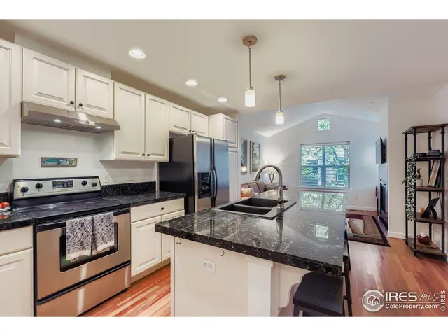 a kitchen with stainless steel appliances granite countertop a stove top oven a sink a dining table and chairs with wooden floor