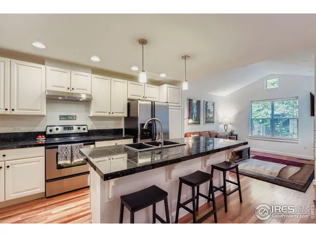 a kitchen with kitchen island granite countertop a table chairs sink and cabinets