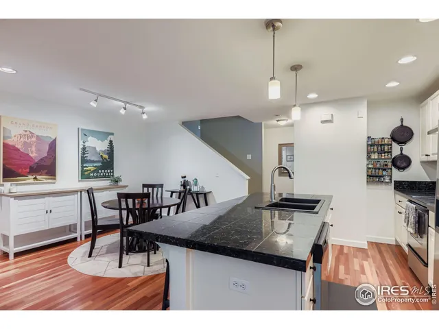 a kitchen with stainless steel appliances granite countertop a sink a stove and chairs with wooden floor