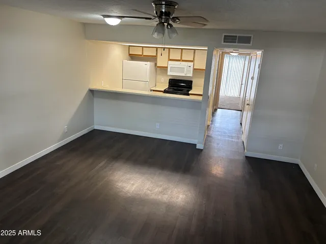 a view of a kitchen with a fridge and wooden floor