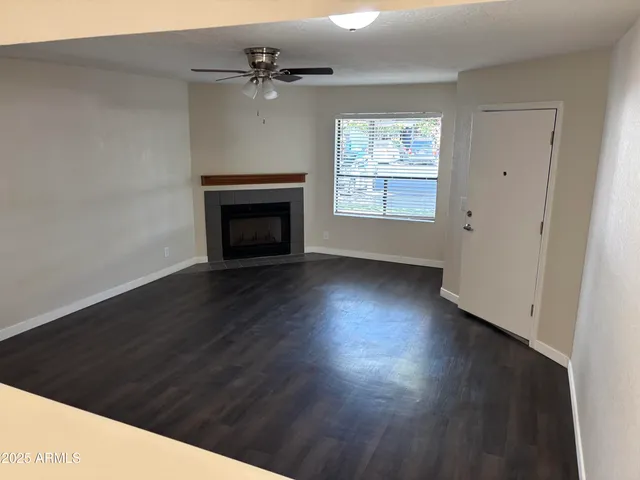 an empty room with wooden floor a fireplace and windows