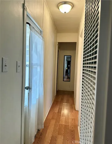 a view of a hallway with wooden floor and a bathroom