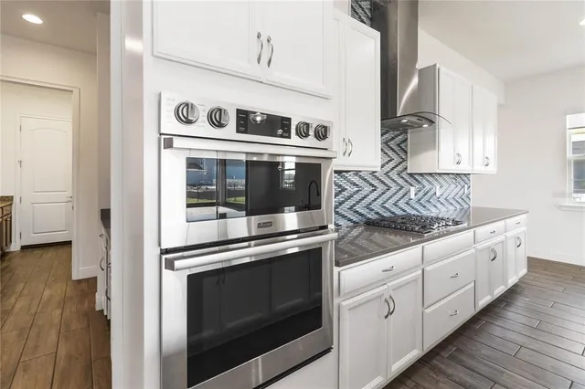a kitchen with stainless steel appliances white cabinets and wooden floor