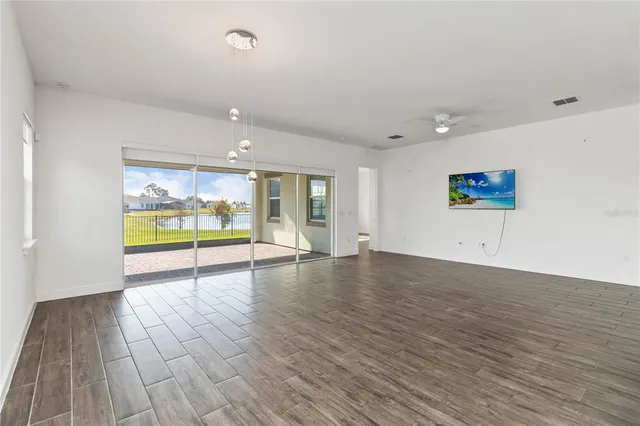 a view of an empty room with wooden floor and windows