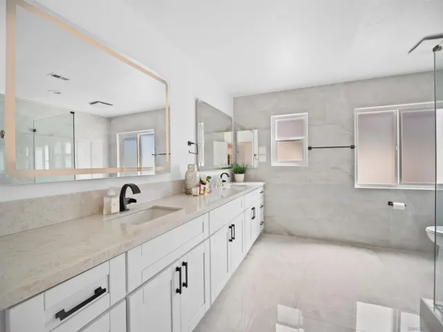 a bathroom with a double vanity sink mirror and a bathtub