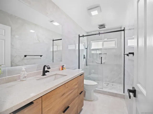 a bathroom with a double vanity sink toilet mirror and shower