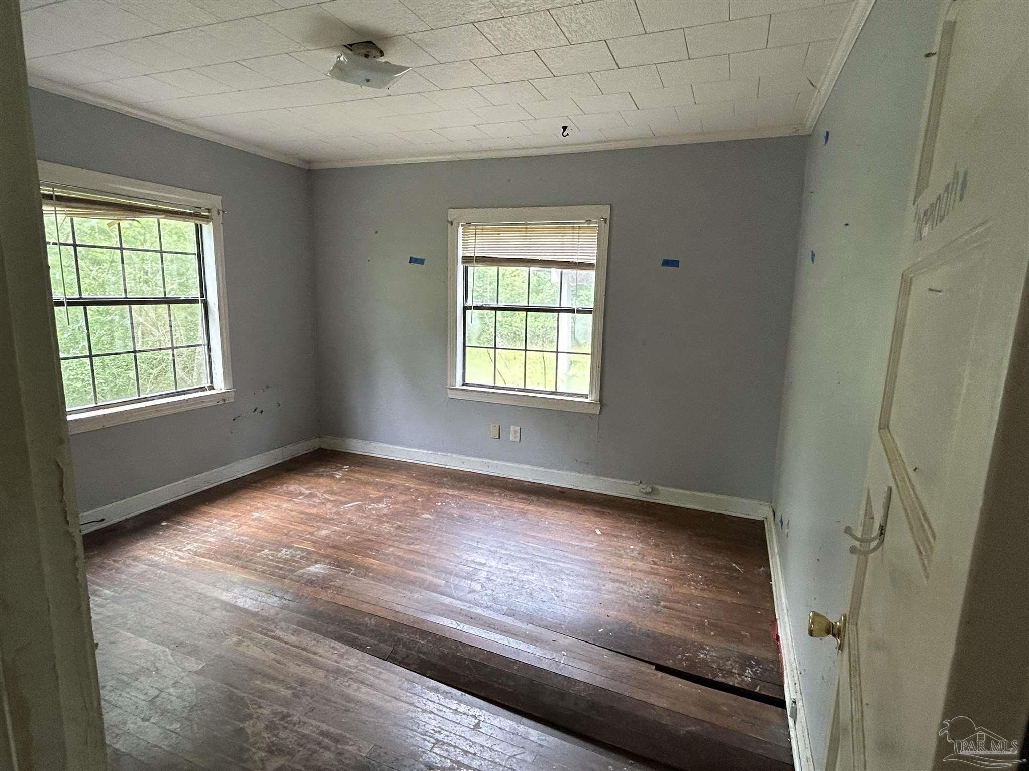 9880 N Loop Pensacola, FL 32507 - Photo 9 of 13 an empty room with wooden floor and windows