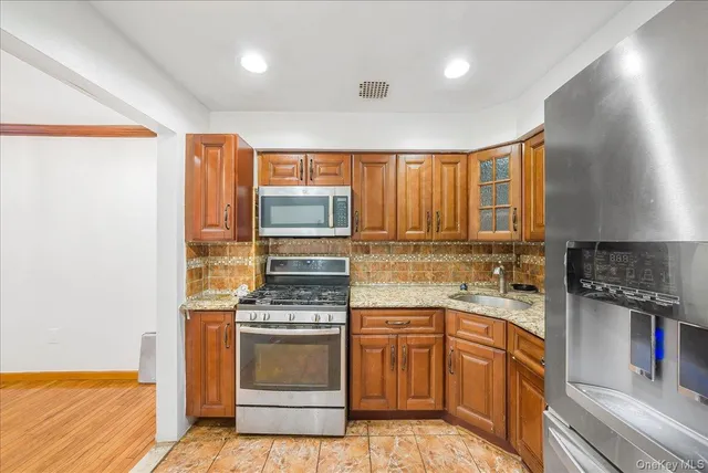 a kitchen with stainless steel appliances granite countertop a stove a sink and a microwave