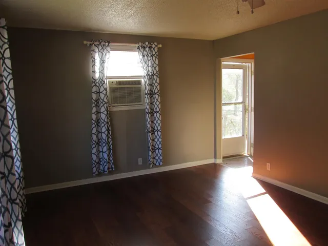 an empty room with wooden floor and windows