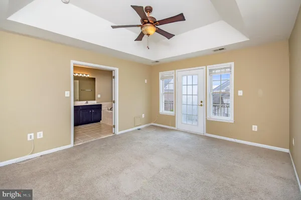 an empty room with chandelier fan and windows