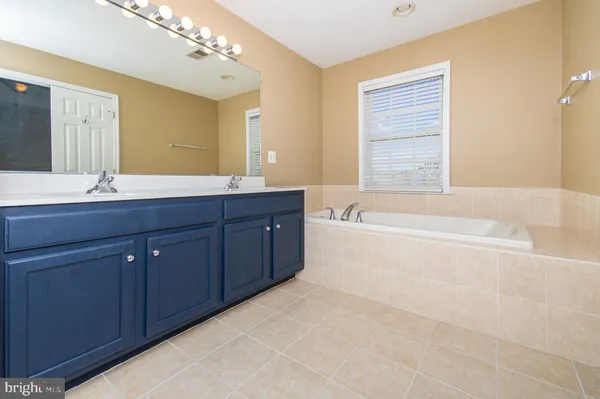 a spacious bathroom with a tub sink and mirror