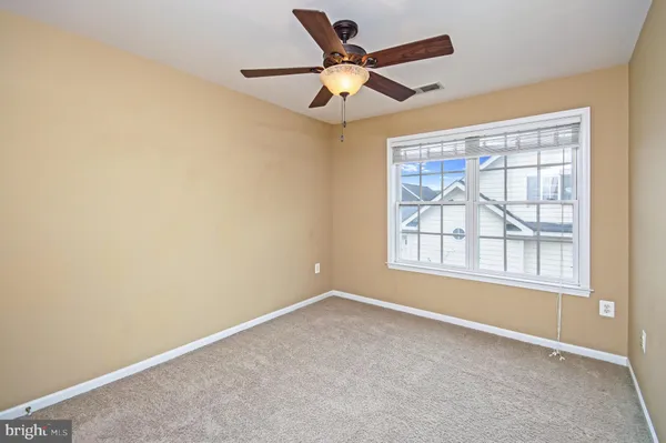 an empty room with a ceiling fan and windows