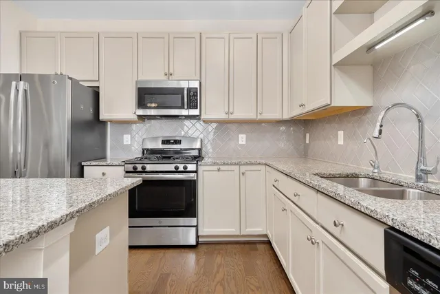 a kitchen with granite countertop white cabinets and stainless steel appliances