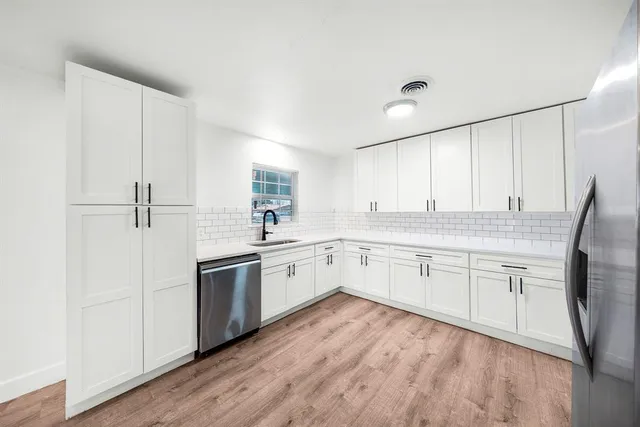 a kitchen with stainless steel appliances granite countertop a stove a sink and white cabinets
